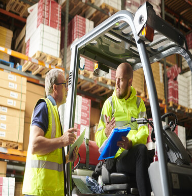 fork lift truck driver in warehouse chats to supervisor